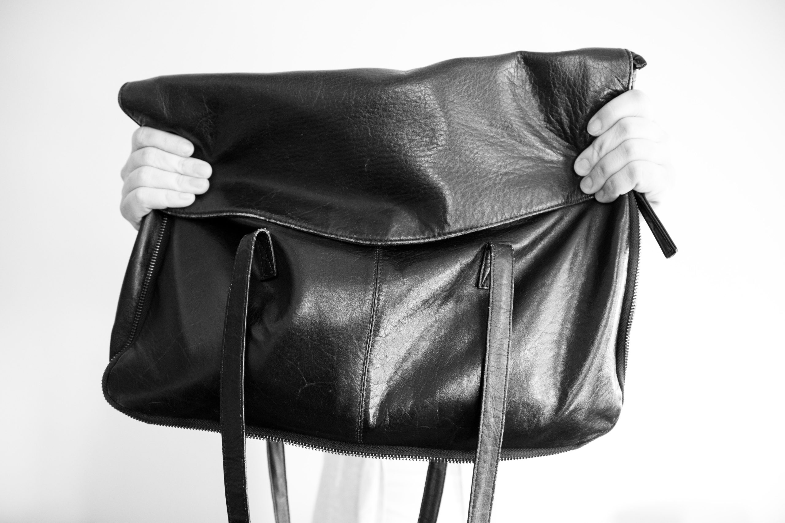 hands holding black bag or purse