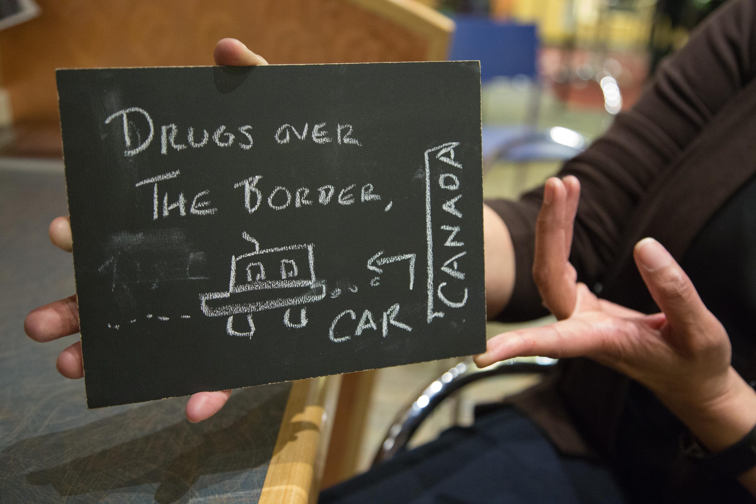 Chalkboard stating Drugs over the border, car, Canada written in chalk