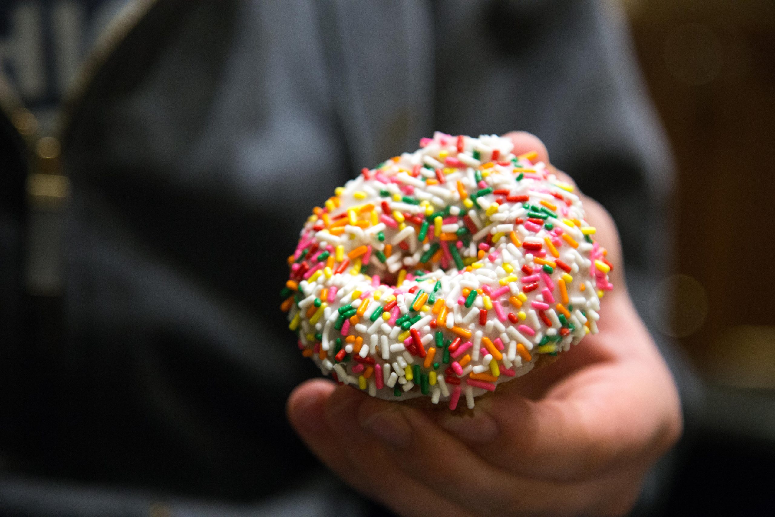 Person holding donut with sprinkles