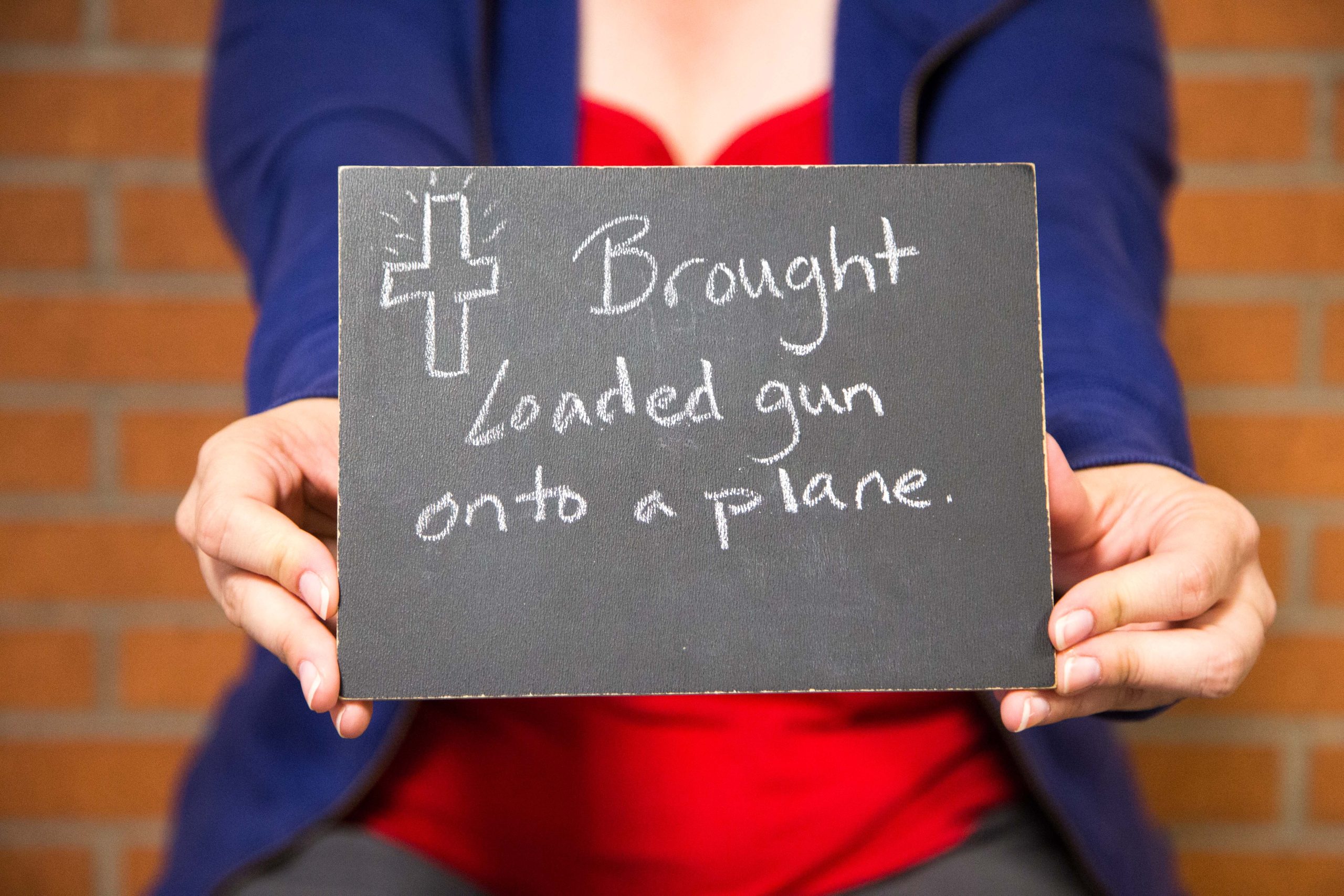 Chalkboard stating Brought Loaded gun onto a plane written in chalk with a cross Chalkboard stating Brought Loaded gun onto a plane written in chalk with a cross