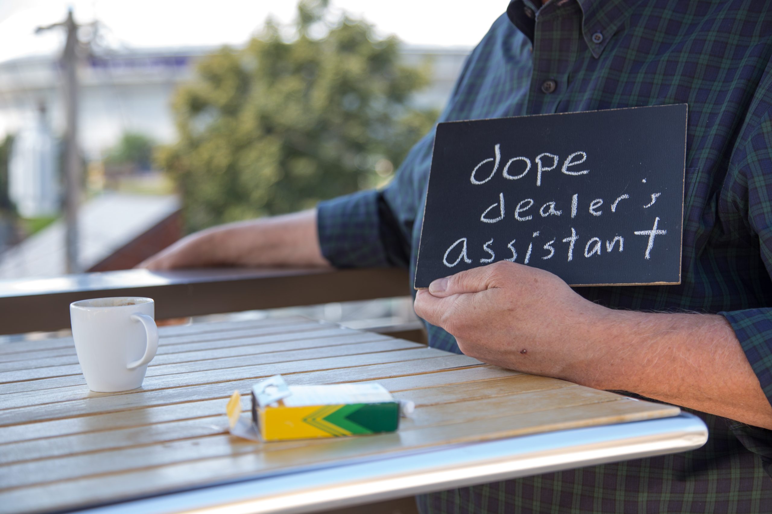 Chalkboard stating dope dealer's assistant written in chalk