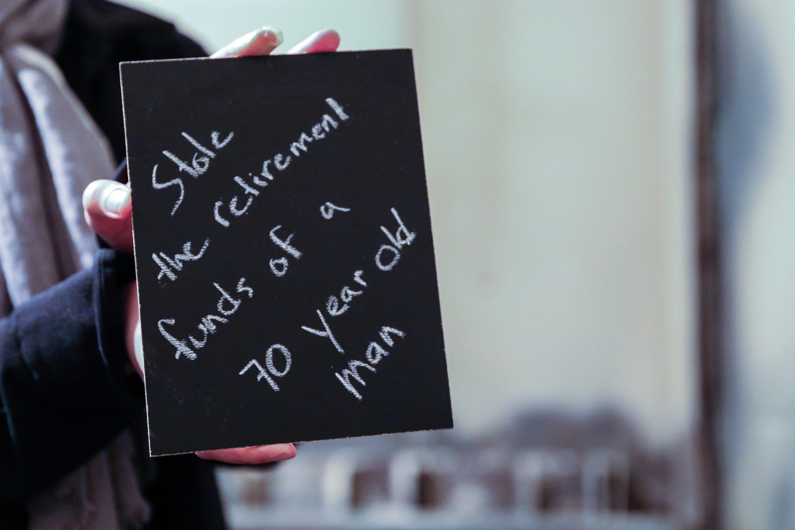 Chalkboard stating Stole the retirement funds of a 70 year old man written in chalk