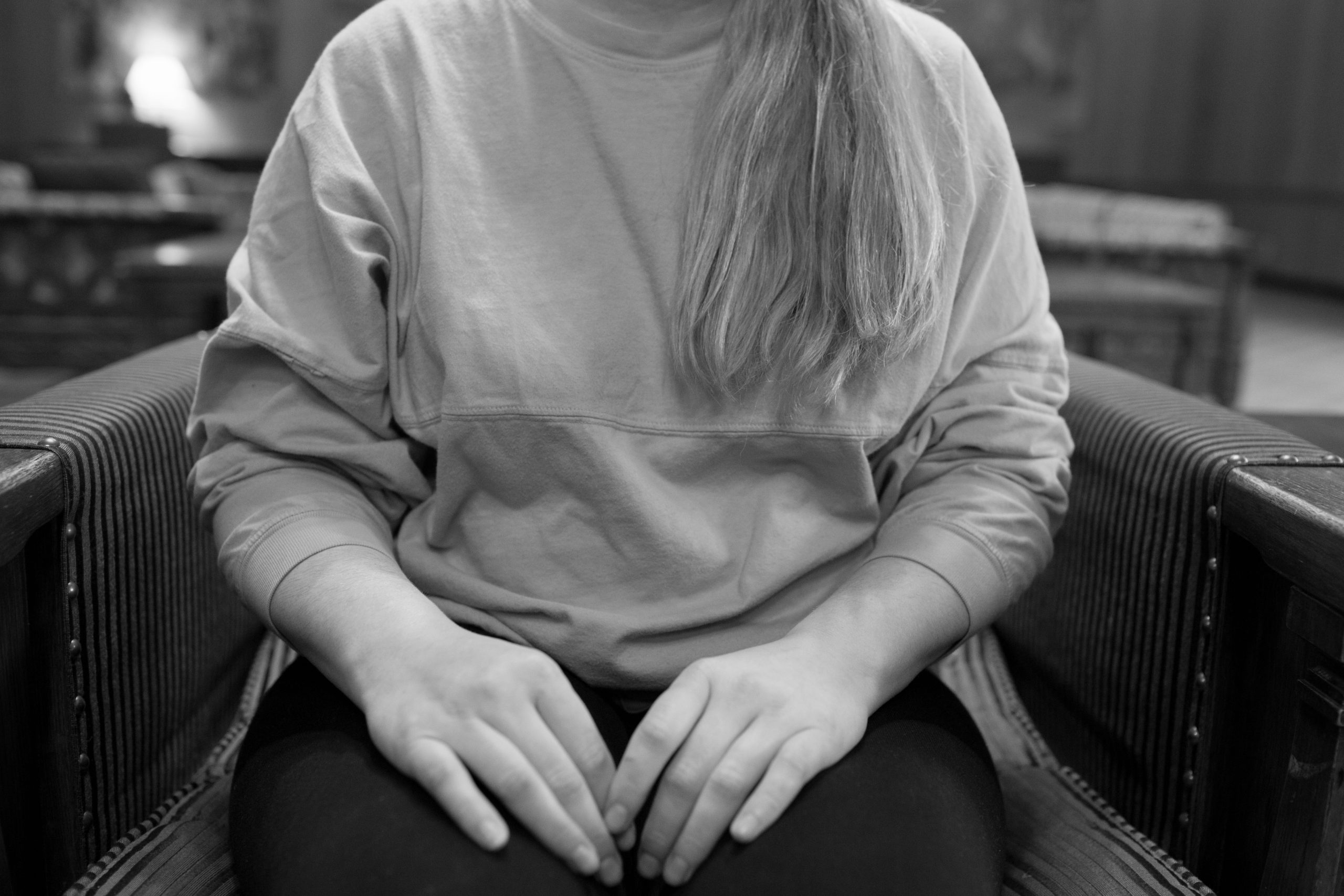 Person with long blond hair in sweatshirt sitting in striped chair