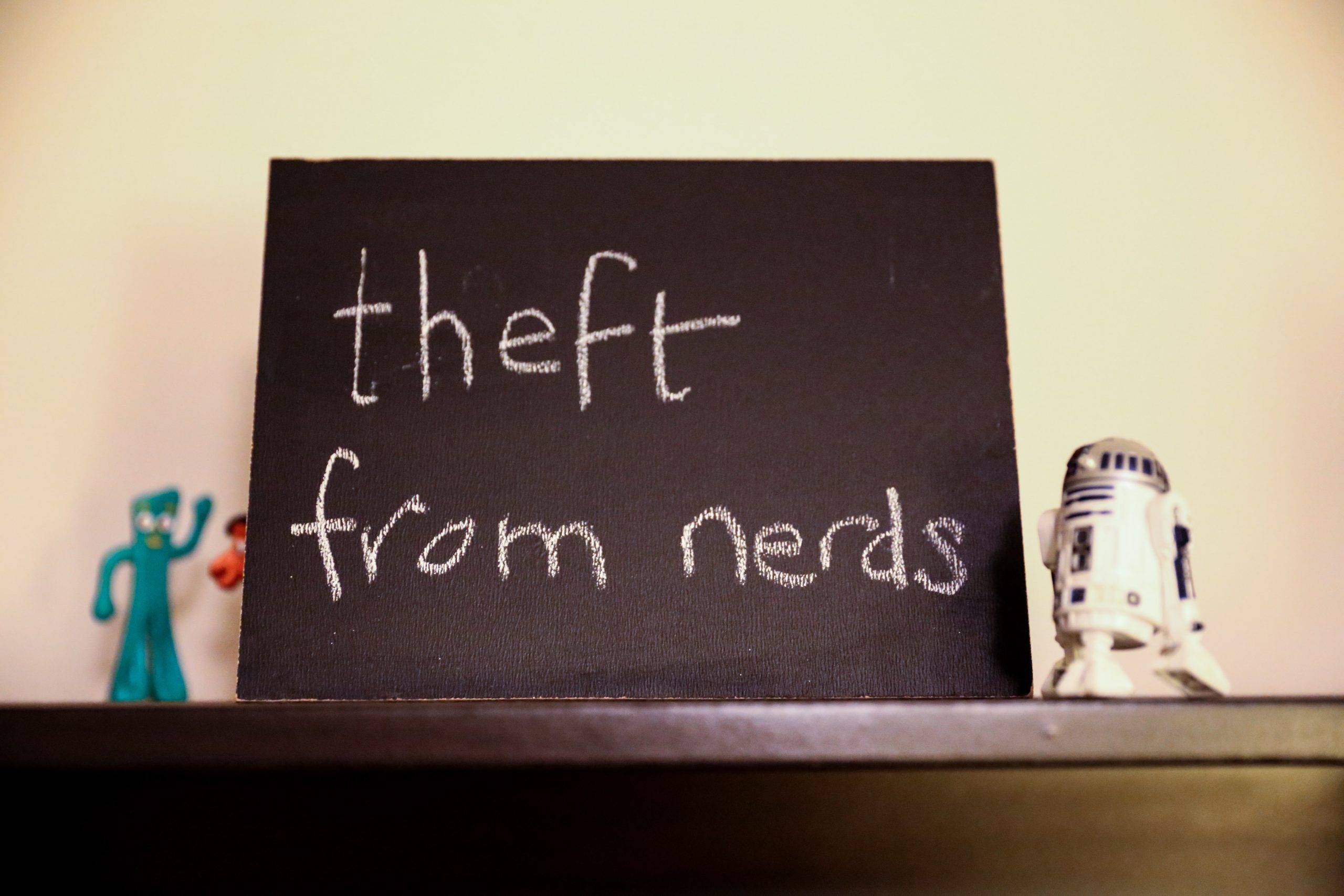 Chalkboard stating theft from nerds written in chalk with Gumby and R2-D2 toys