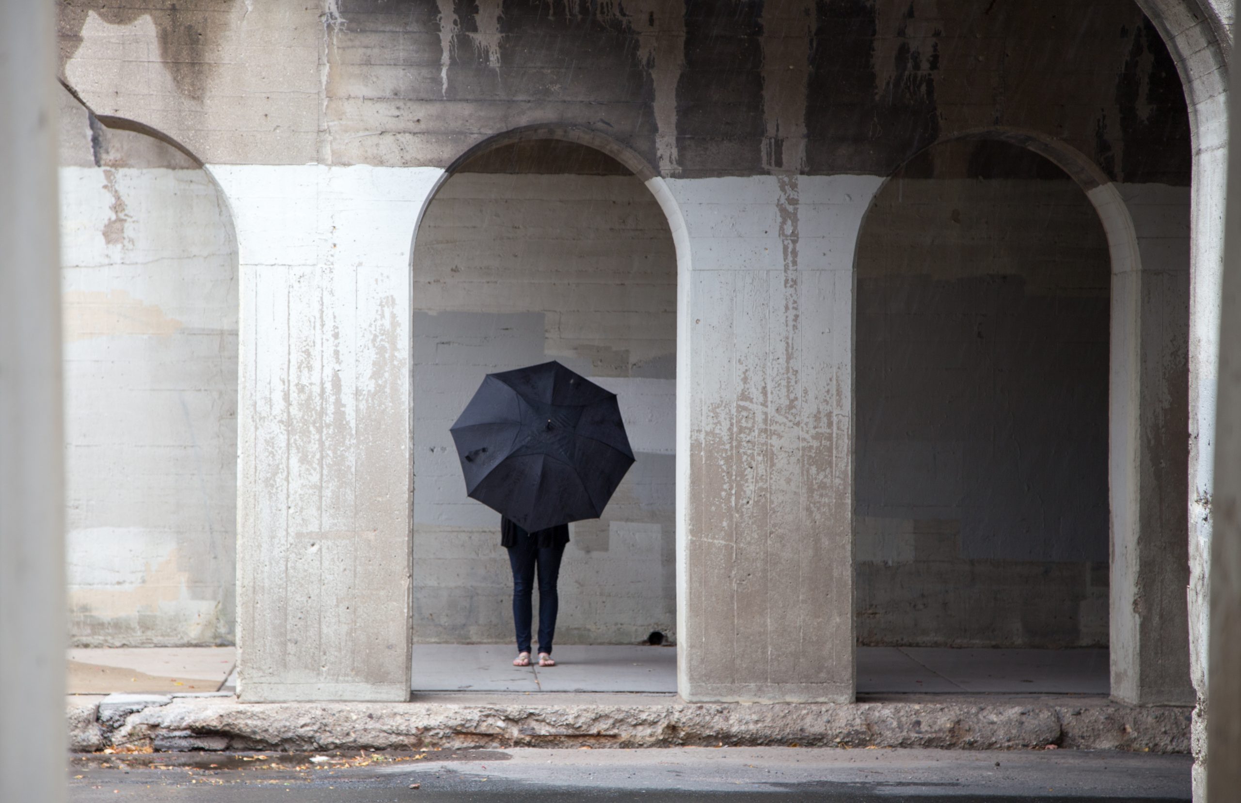 Person holding black umbrella in arches Person holding black umbrella in arches