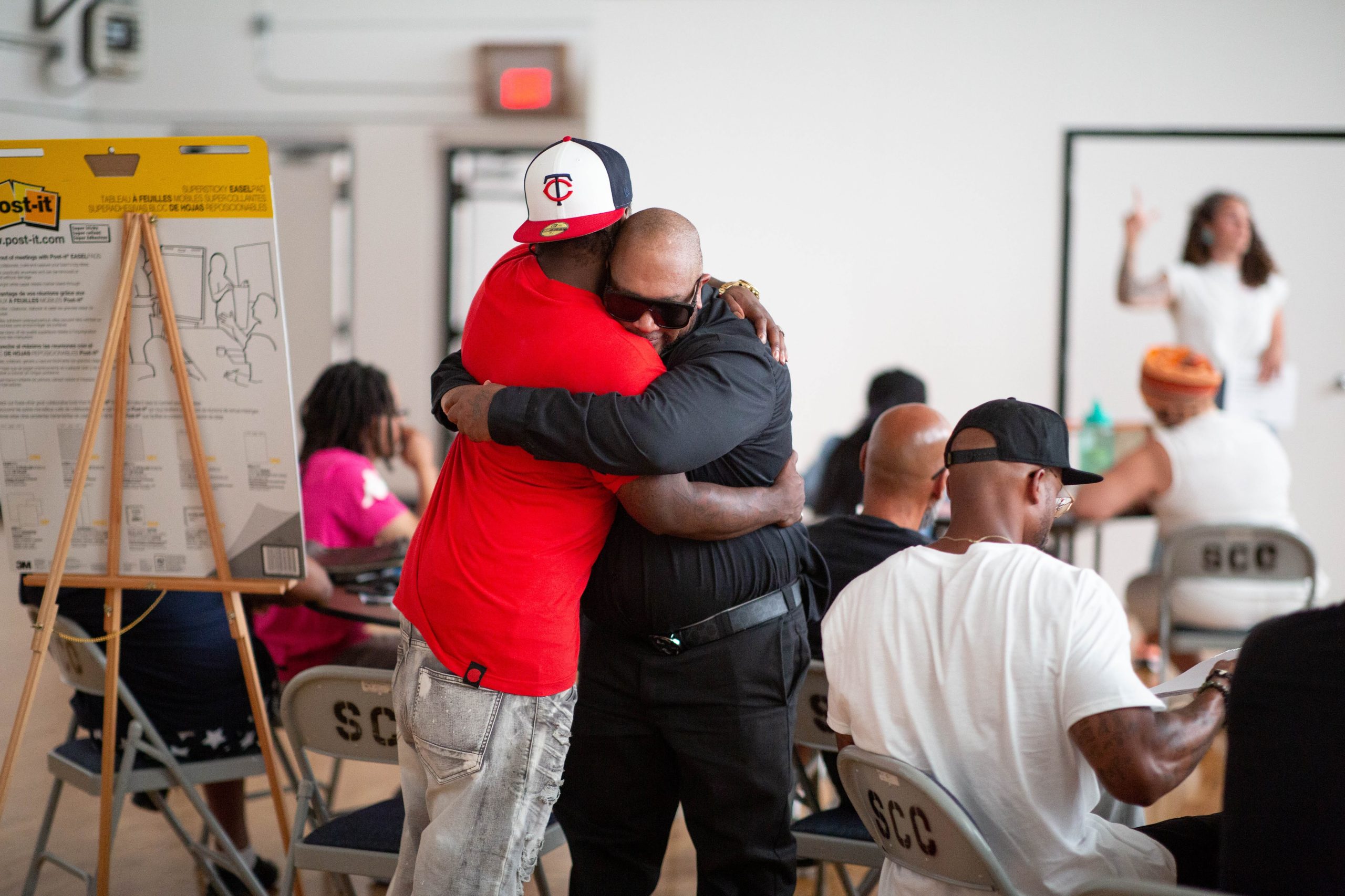 Two men hugging in the midst of a meeting