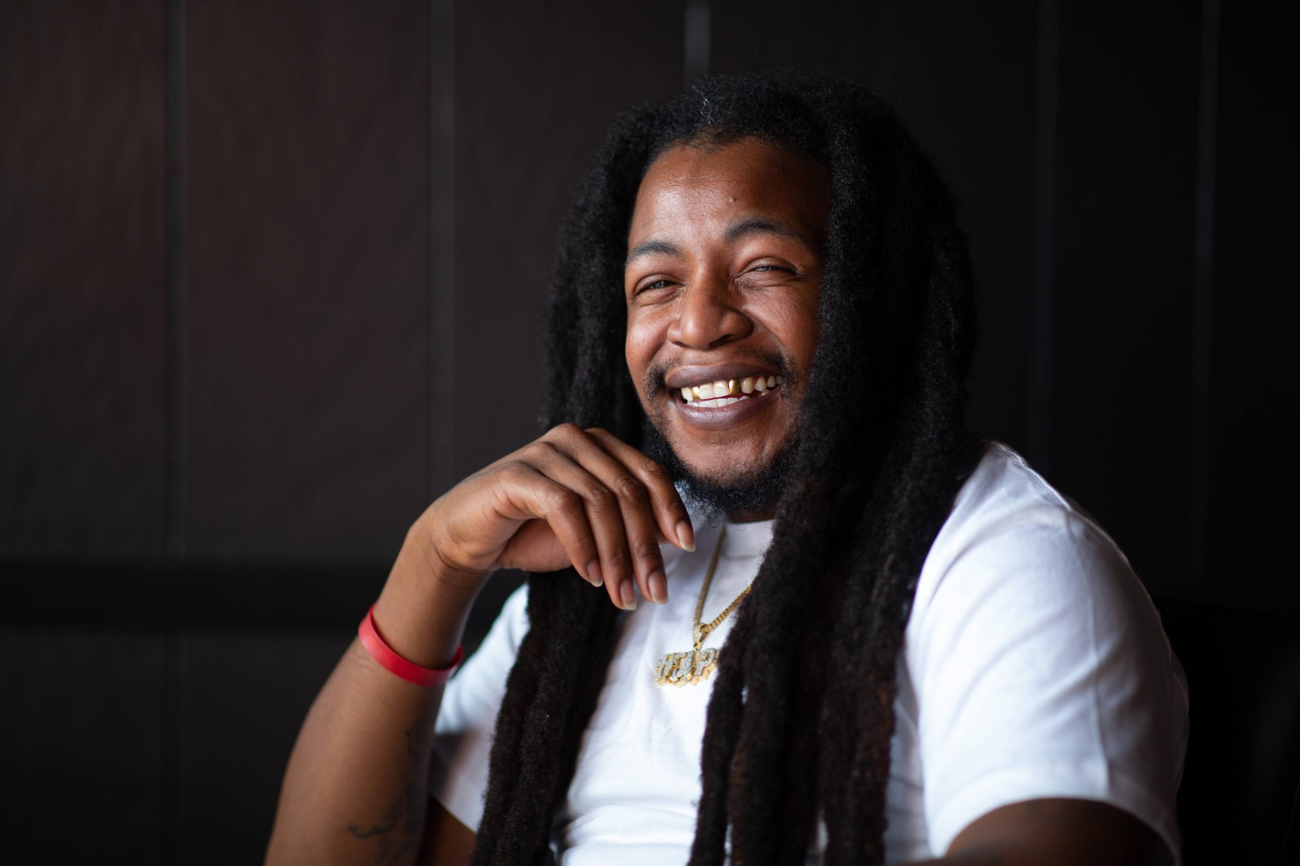 Small child in shorts, t-shirt, and rain boots, standing in a playing field next to a soccer net, holding a large yellow rubber ball in front of her face