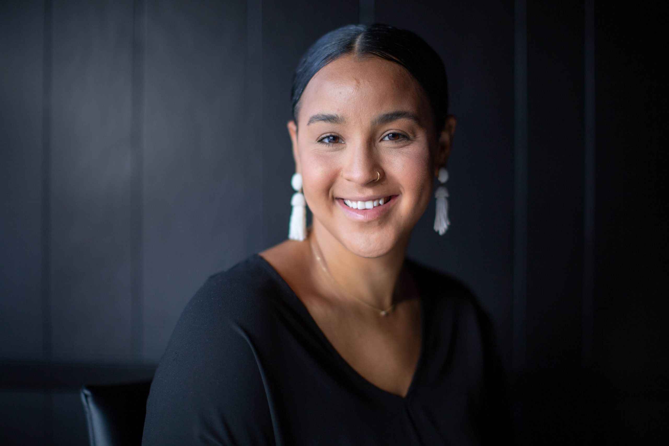 Maya smiling in front of a black background