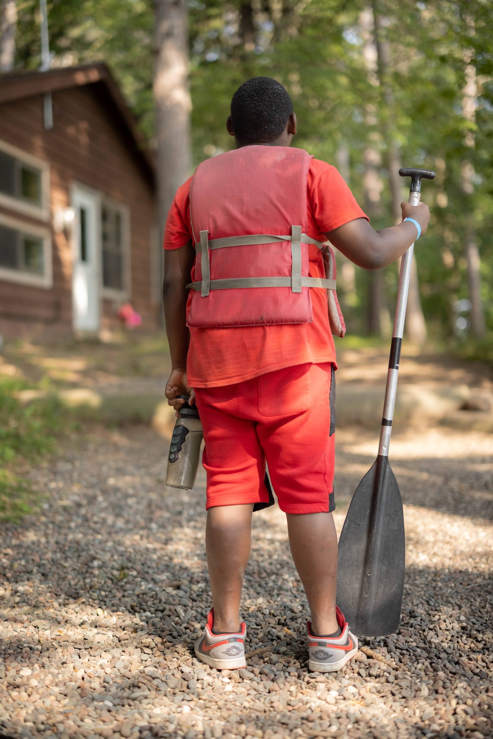 Child in red clothes with a red life vest, holding an oar