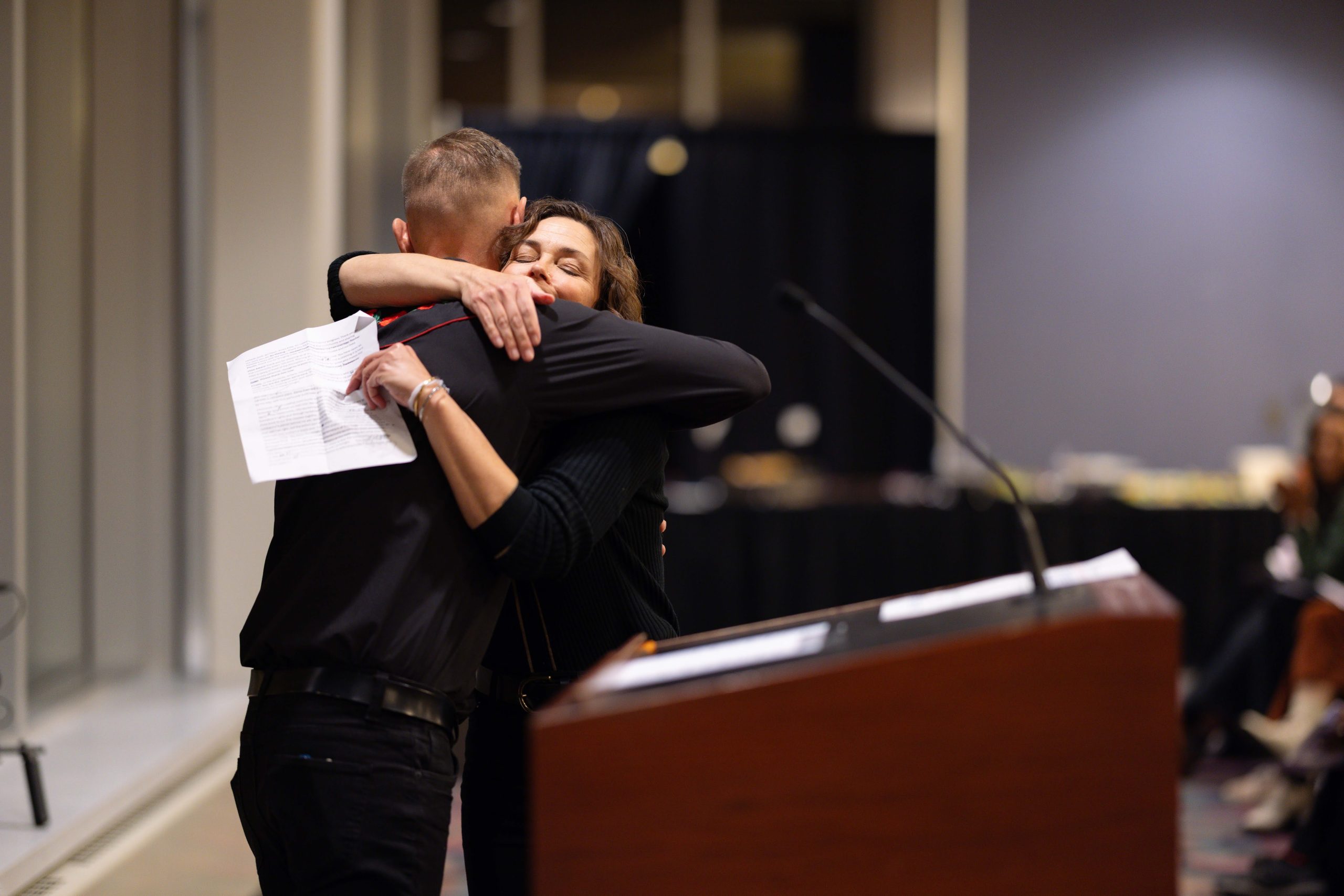 MPWW founder and author Jen Bowen, hugging Zeke Caliguiri at the microphone