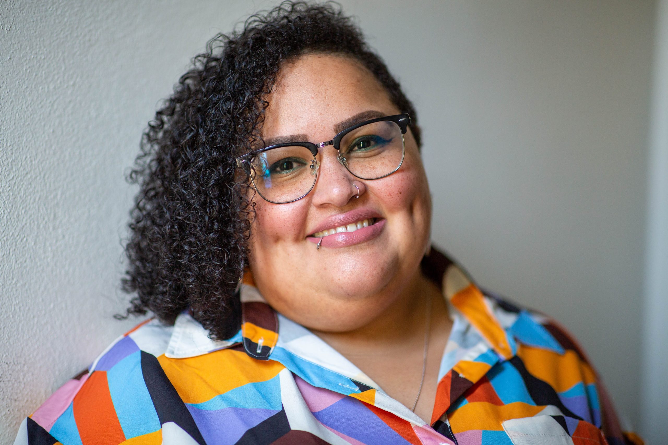 Kahlee and daughter in front of Kahlee's portrait in the Hennepin Theatre Trusts' sidewalk exhibit. She is taking a selfie and looking toward the sun