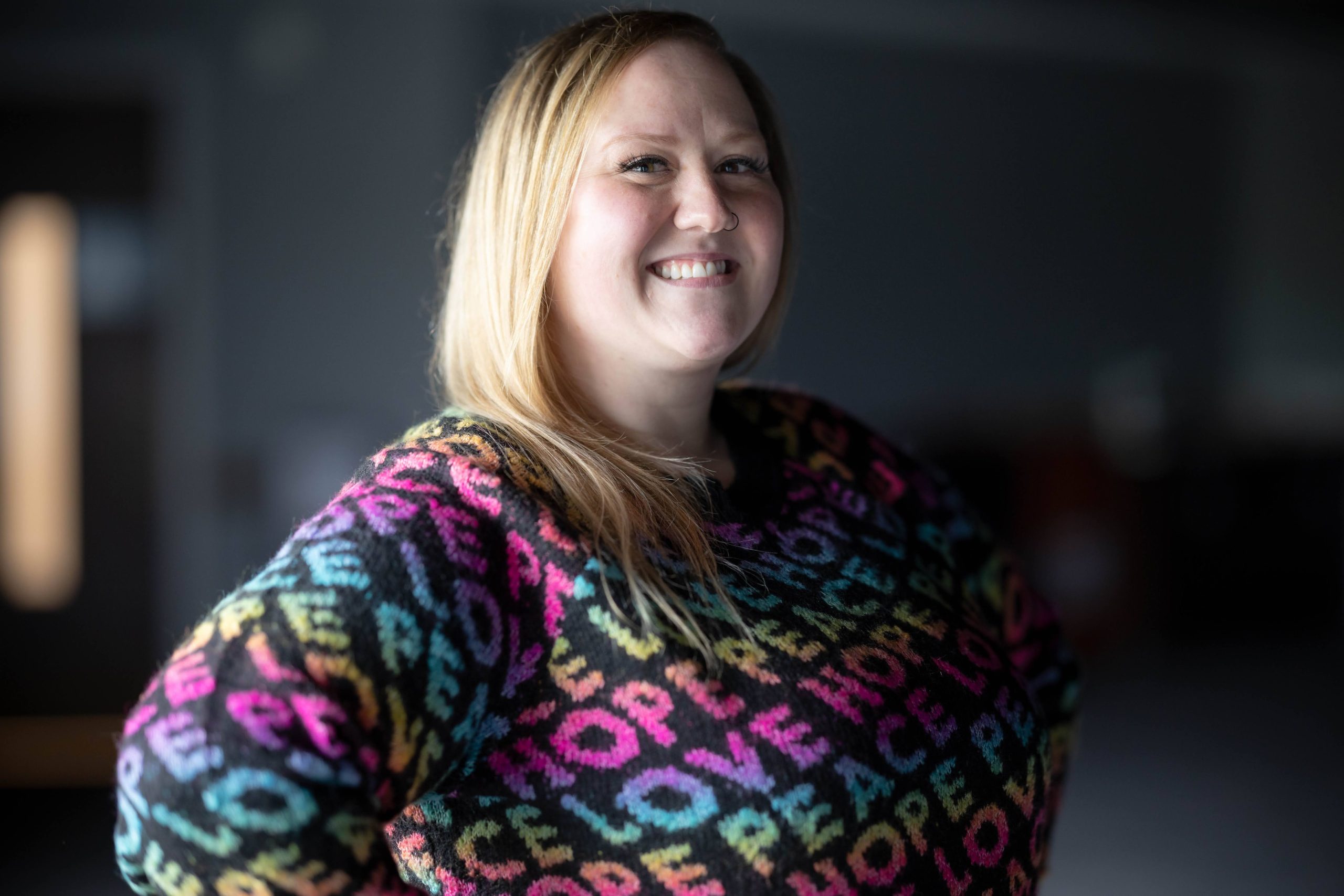 Woman in colorful sweater, smiling at the camera