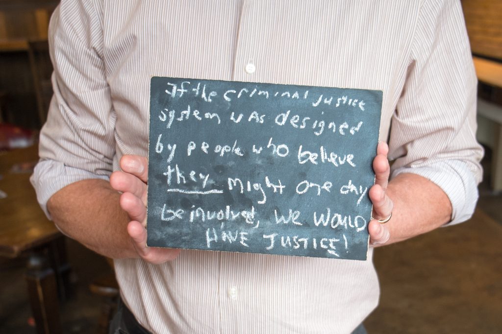 Chalkboard stating If the criminal justice system was designed by people who believe they might one day be involved, we would have justice! written in chalk